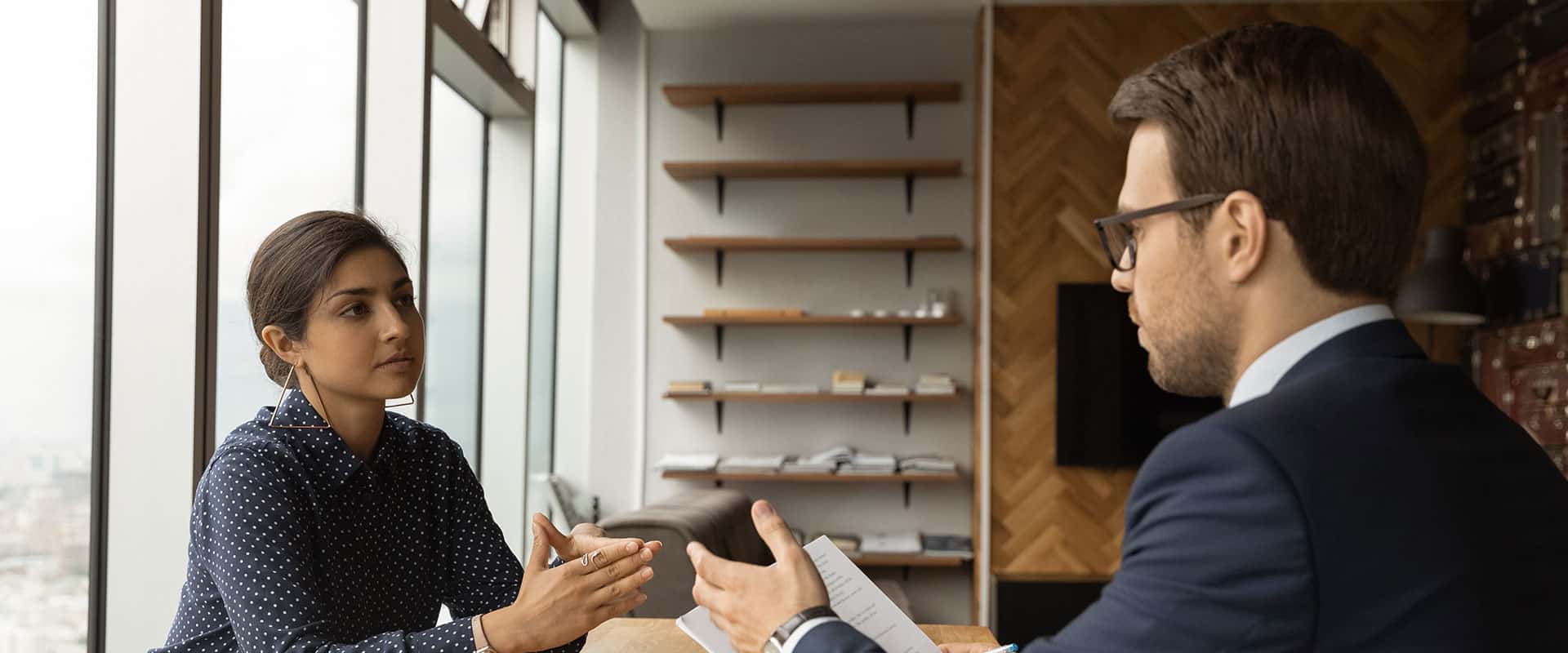 A man and woman talking at a table in an office.