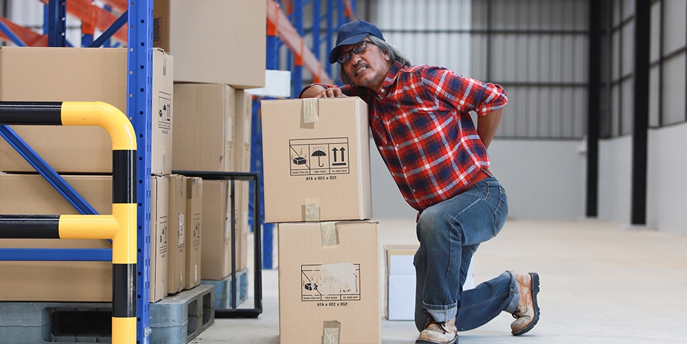 A man leaning on a box in a warehouse.