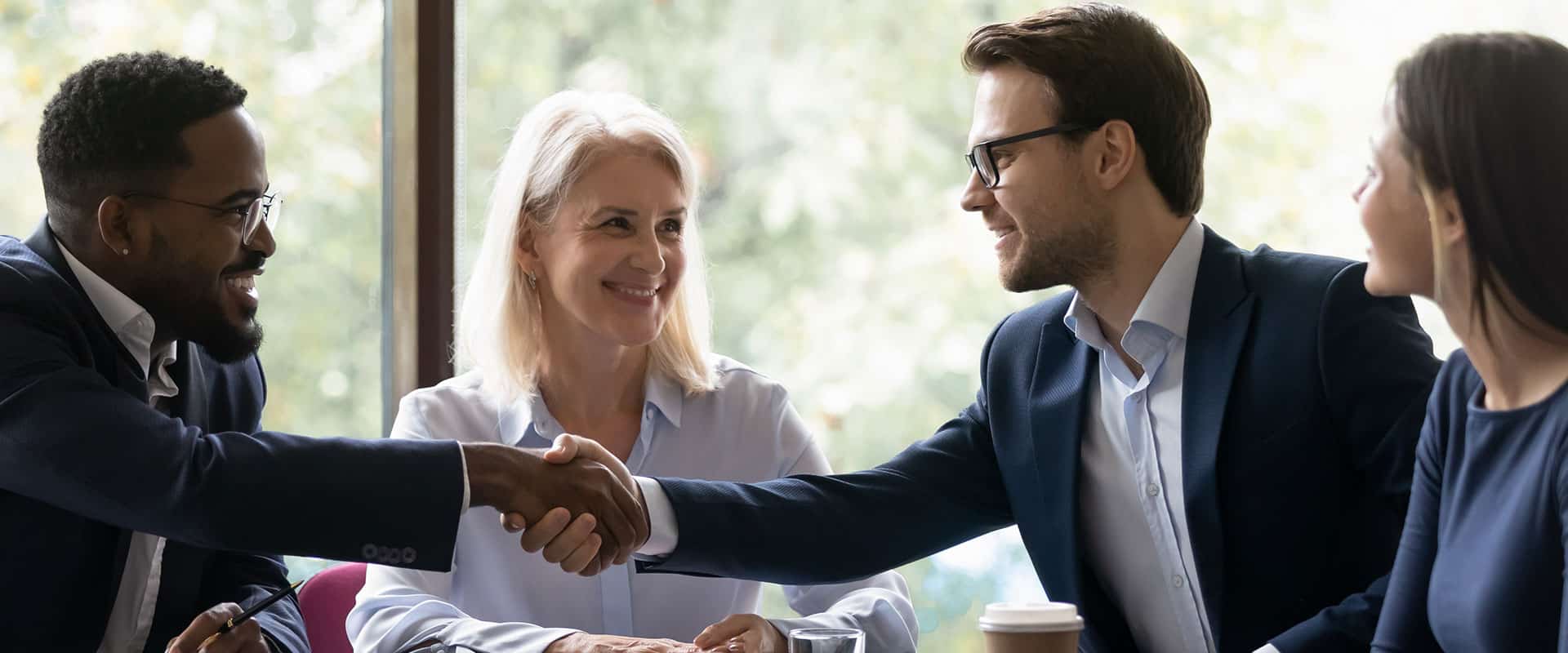 A group of business people shaking hands at a meeting.