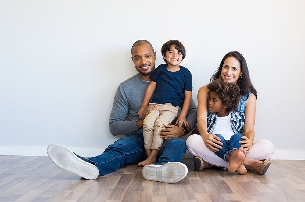 A family sitting on the floor in an empty room.